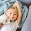 Little toddler child, boy, lying in bed with pet dog, little maltese puppy dog